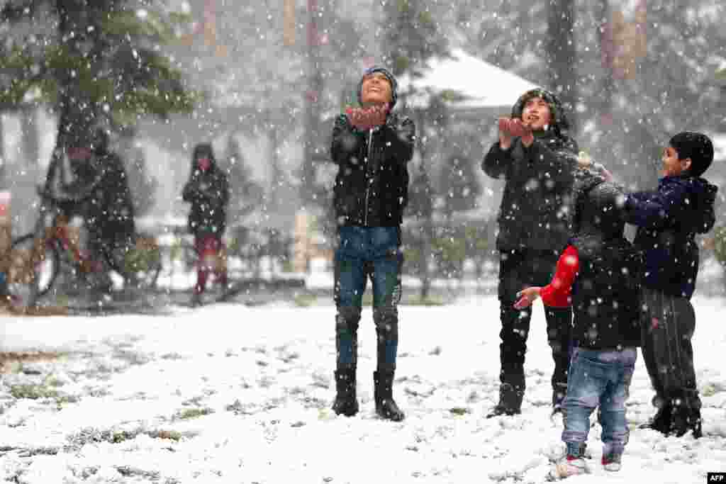 Boys play in a park during a snowfall in Kabul.