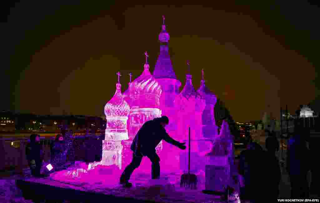 A man cleans snow in front of an ice sculpture during the Snow And Ice festival in Moscow.