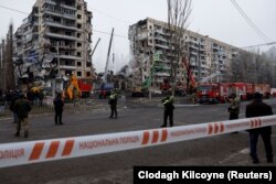 Люди спостерігають, як надзвичайники працюють на місці, де житловий будинок був сильно пошкоджений російським ракетним ударом під час атаки РФ в Дніпрі