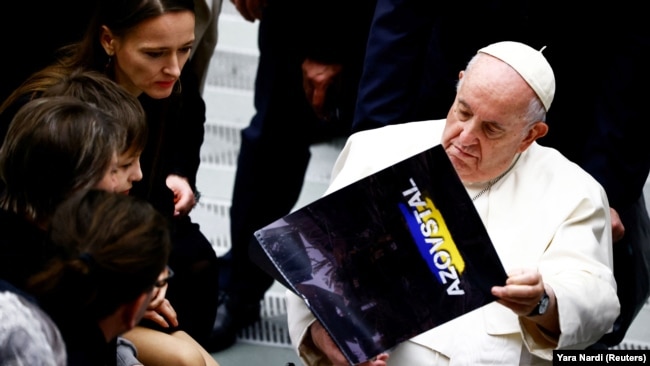 Папа римский Франциск держит в руках календарь, переданный ему Юлией Федосюк. 21 декабря 2022 года
