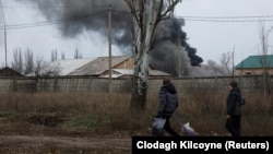 A couple walks past an industrial building that was hit by a missile strike on the front line in eastern Ukraine on December 25. 