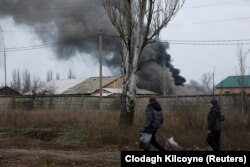 Imagine din Bahmut, estul Ucrainei. Doi locuitori merg într-o zonă industrială la scurt timp după ce o bombă a lovit o clădire.