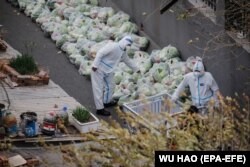 Lucrători sanitari voluntari pregătesc saci cu legume pentru locuitorii aflați în izolare în Beijing, China, 28 noiembrie 2022.