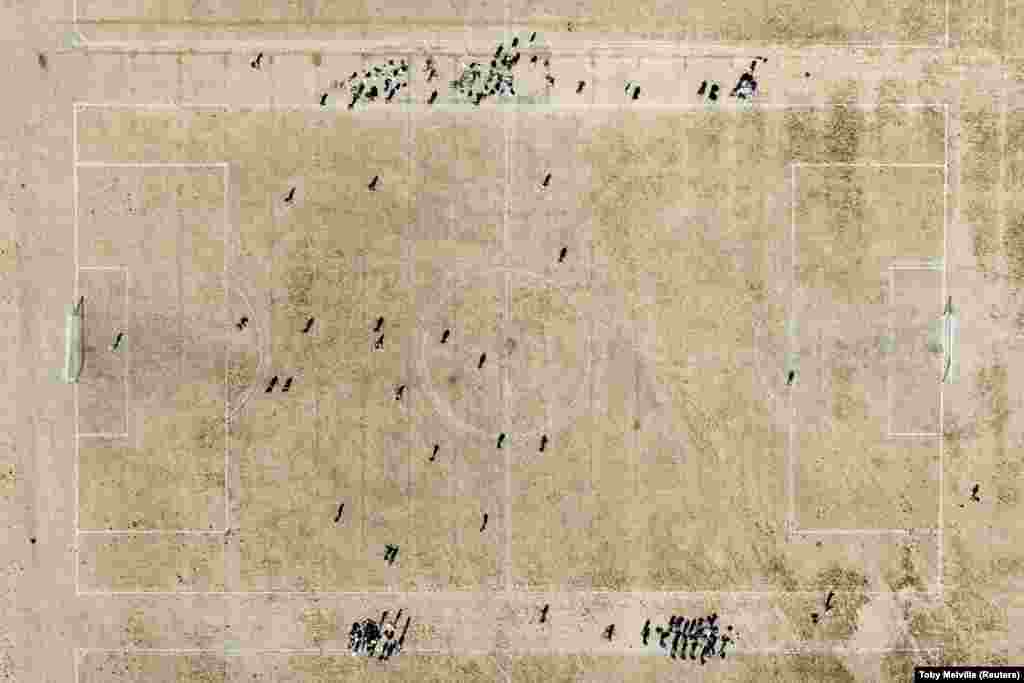 Луѓе играат фудбалски натпревар на исушена трева за време на топлотен бран, во Хакни Маршс во Лондон, Британија на 14 август 2022 година. (Ројтерс/Тоби Мелвил)