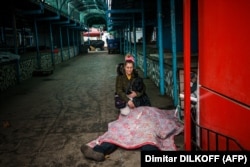 Egy nő térdel halott férje mellett, aki december 24-én orosz ágyúzásban halt meg