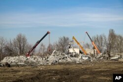 Робітники розчищають завали після влучання ракет, випущених по будівлі в Макіївці в новорічну ніч на 2023 рік. 3 січня 2023 року