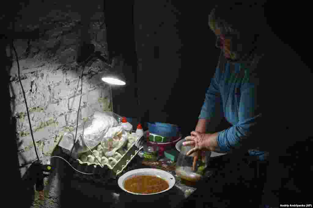 Жінка миє посуд в одному із підвалів будинку у місті Соледар.