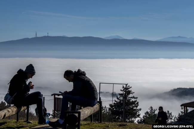 Njerëzit duke shijuar një ditë me diell në malin afër fshatit Kuçkovë, ndërsa mjegulla dhe ndotja kanë mbuluar Shkupin, Maqedoni e Veriut, 02 janar 2023.