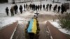 Ukrán katonák viszik a vállukon egyik elesett bajtársuk koporsóját Bucsában 2023. január 12-én
