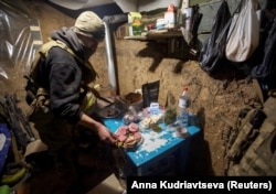 Një pjesëtar i shërbimit ukrainas përgatit ushqim në një strehë afër pozicionit të tyre në vijën e parë të frontit, mes sulmeve të Rusisë ndaj Ukrainës, në rajonin e Donjeckut, Ukrainë, 1 janar 2023.