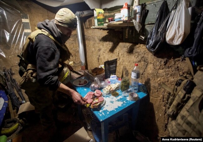 Një pjesëtar i shërbimit ukrainas përgatit ushqim në një strehë afër pozicionit të tyre në vijën e parë të frontit, mes sulmeve të Rusisë ndaj Ukrainës, në rajonin e Donjeckut, Ukrainë, 1 janar 2023.