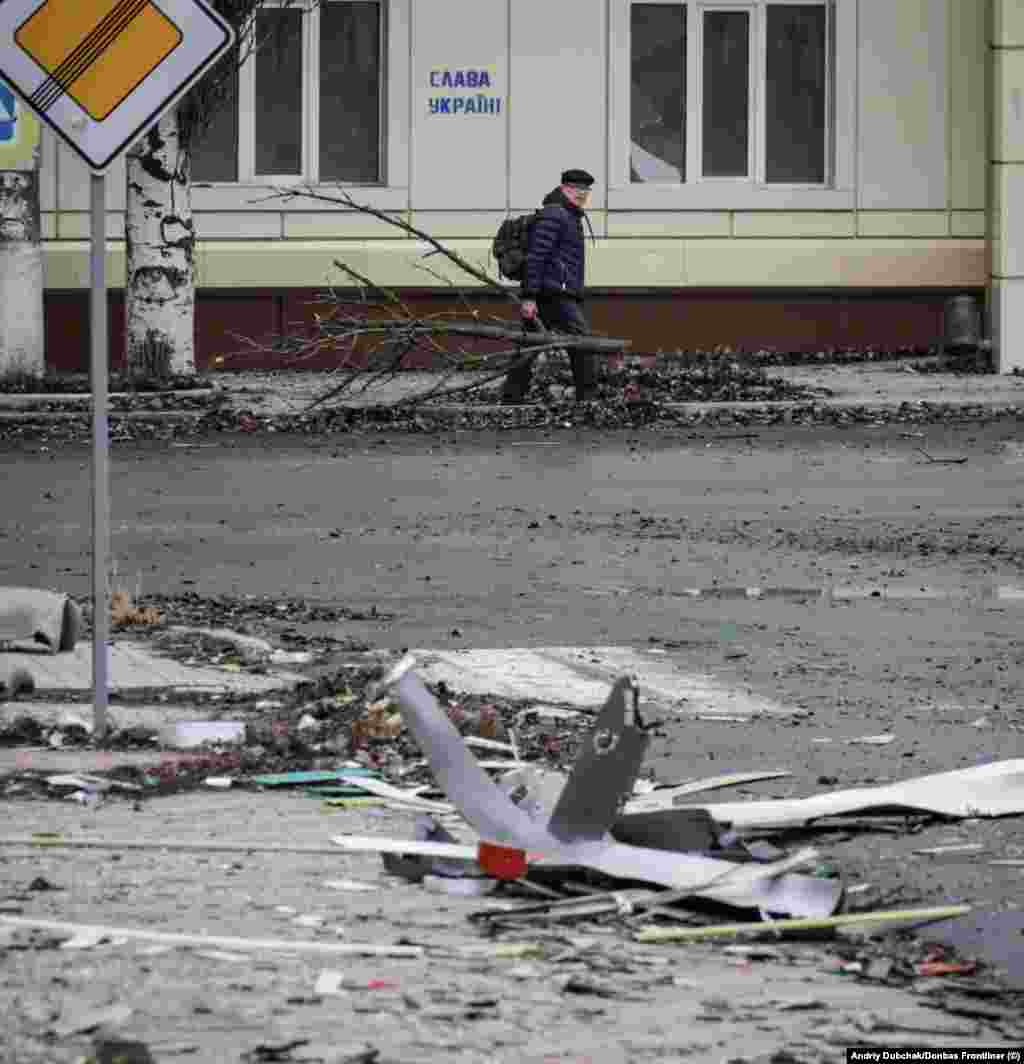 Një burrë duke bartur një degë peme që do ta përdorë për dru zjarri, kurse në murin pranë tij shihet një grafit: &quot;Lavdi Ukrainës!&quot; Dubchak thotë se arsyet pse po qëndrojnë banorët në qytet janë të ndryshme, si mbrojtja e pronave të tyre apo frika se si do të ishte jeta si një person i zhvendosur brenda vendit. Sipas Dubchakut, ka edhe disa civilë që presin ardhjen e &quot;botës ruse&quot; të premtuar në propagandën e Kremlinit.