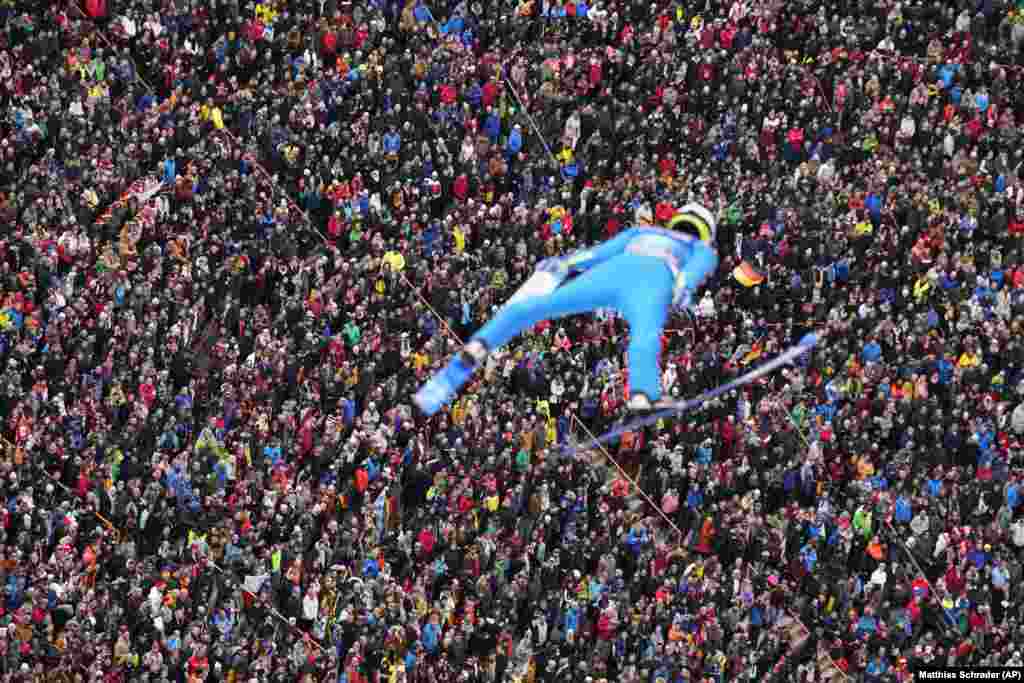 Людзі глядзяць, як казахстанец Даніл Васільеў узьлятае ў паветра на трэцім этапе 71-га турніру па скачках з трампліна ў Інсбруку, Аўстрыя.