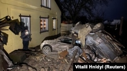 A man stands next to cars destroyed by a Russian missile strike in a residential area in Kharkiv on December 8.