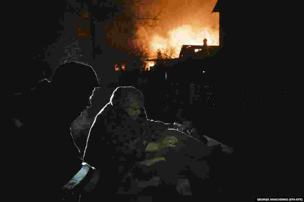 A local woman collects things near a burning building after Russian shelling in the village of Ivanivka near Bakhmut in Ukraine&#39;s Donetsk region.&nbsp;