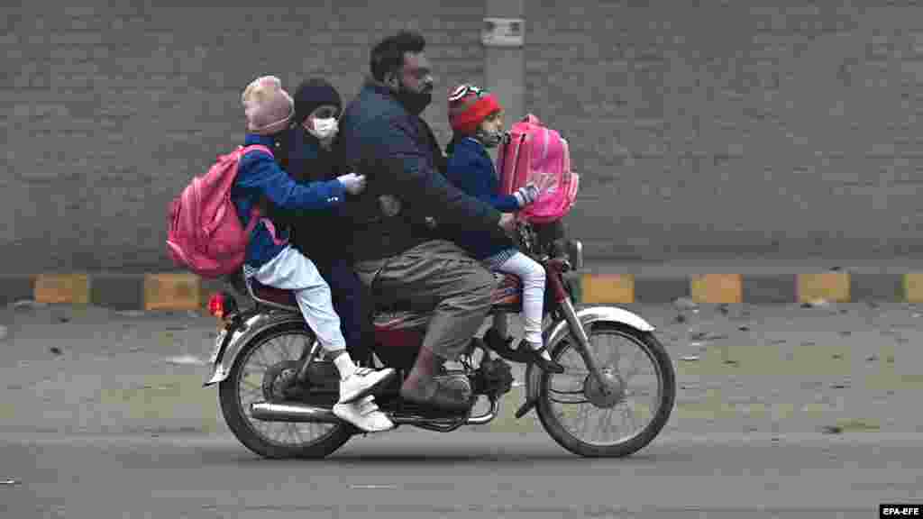 Muškarac vozi decu u školu na motociklu u pakistanskom gradu Lahore