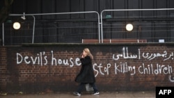 Pedestrians walk past graffiti daubed on a wall outside the Iranian Embassy in London on January 14.