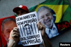 Prodemokratski demonstrant drži plakat tokom marša sa slikom na kojoj je prikazan bivši predsednik ekstremne desnice Jair Bolsonaro i natpis „Bez amnestije, bez pomilovanja, Bolsonaro u zatvor“, u Porto Alegreu, Brazil 9. januara 2023