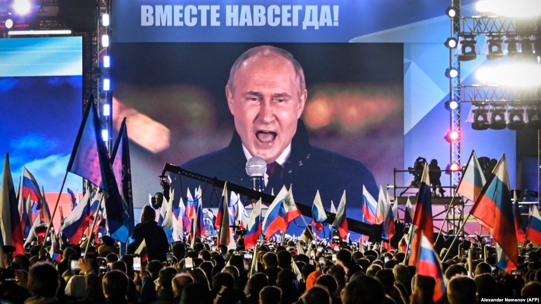 Președintele rus Vladimir Putin, văzut pe un ecran în Piața Roșie din Moscova, în septembrie 2022, în timp ce se adresează mulțimii despre așa-zisa reunire cu Rusia a patru regiuni parțial ocupate din Ucraina.