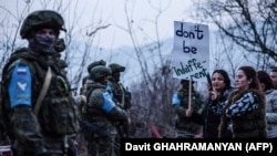 Nagorno-Karabakh - Azerbaijani protesters stand in front of Russian peacekeepers on a road outside Stepanakert, December 24, 2022. 