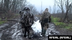 Українські військові несуть тіло загиблого військового РФ, щоб згодом обміняти його на тіло свого побратима, фото ілюстративне