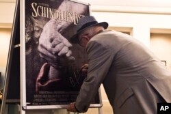 Хърватинът Бранко Лустиг, оцелял от от Аушвиц, подписва плакат на филма "Списъкът на Шиндлер" преди церемония в мемориала на Холокоста "Яд Вашем" в Йерусалим, 2015 г. Лустиг е един от продуцентите на филма.