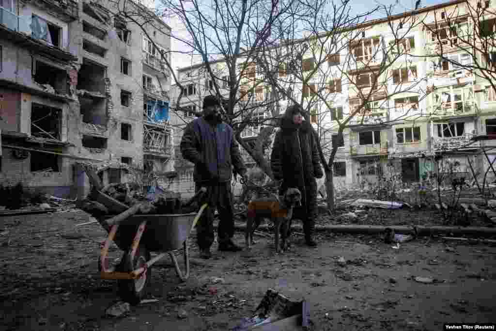 Bakhmut residents stand near a wheelbarrow used to collect firewood near their destroyed apartment. On December 6, the UN&#39;s humanitarian chief, Martin Griffiths, decried the &quot;colossal&quot; torment that Ukraine is suffering from Russia&#39;s destruction of its infrastructure.