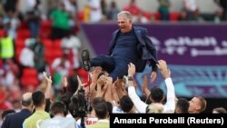 Iranian players celebrate with coach Carlos Queiroz after the match against Wales on November 25.