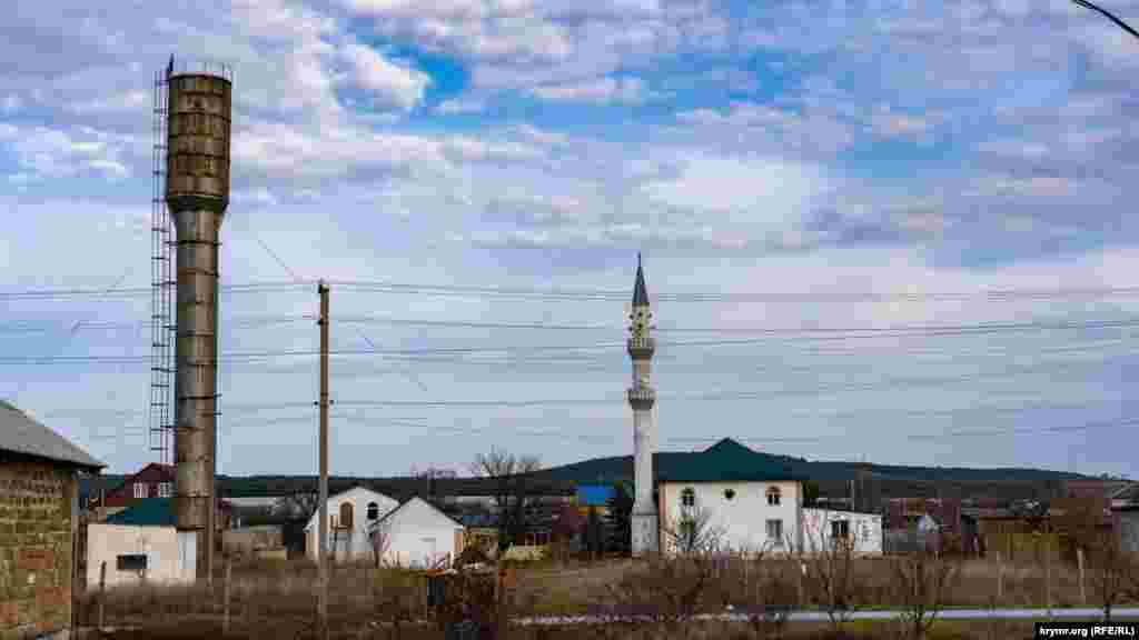 Водонапорная башня с крымскотатарским флагом наверху на фоне мечети Сарысу-Джами