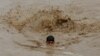 A man swims in floodwaters while heading for higher ground during the monsoon season in Charsadda, Pakistan, on August 27, 2022.