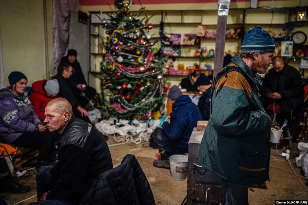 Disa njerëz shihen afër pemës së Krishtlindjes në një qendër humanitare në Bahmut, qytet në lindje të Ukrainës. &nbsp;