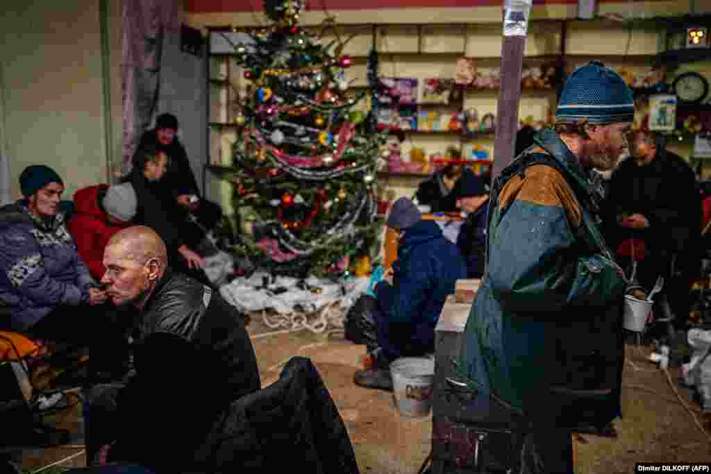 People gather around a Christmas tree as they rest inside a humanitarian aid center in Bakhmut, in Ukraine&#39;s eastern Donetsk region, on January 6.