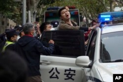 Un protestatar chinez este arestat de polițiști în timpul unui protest din Shanghai, China, 27 noiembrie 2022.