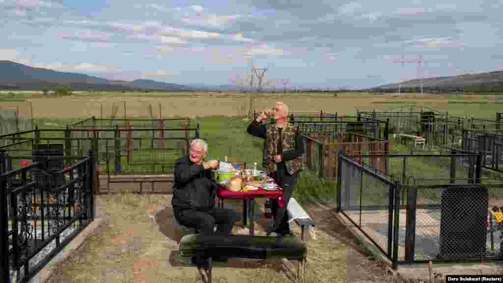 Egy oszét és egy georgiai férfi eszik egy asztalnál a khurvaleti temetőnél, miután meglátogatták a rokonok sírját 2019. április 29-én. A háború után felállított szögesdrót kerítés Khurvaleti település kertjein keresztül húzódik, családokat szakítva el egymástól, vagy épp a megélhetést biztosító veteményest, gyümölcsöst kerítve el a gazdáktól