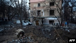 Војник собира делови од проектил по руски напад пред станбена зграда во Киев, на 31 декември 2022 година