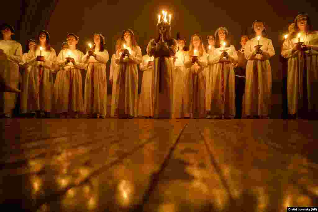 Young women sing carols as they hold candles to celebrate St. Lucia&#39;s Day at the Evangelical Lutheran Church of St. Catherine in St. Petersburg, Russia, on December 13.