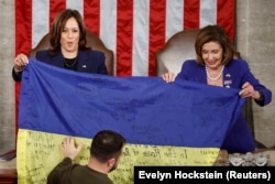 U.S. Vice President Kamala Harris (left) and U.S. House Speaker Nancy Pelosi hold up a Ukrainian flag as Volodymyr Zelenskiy speaks before a joint meeting of the U.S. Congress in Washington on December 21.