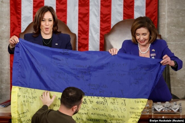 La vicepresidente degli Stati Uniti Kamala Harris e l'allora presidente della Camera Nancy Pelosi tengono una bandiera ucraina mentre Zelenskiy partecipa a una riunione congiunta del Congresso degli Stati Uniti il ​​21 dicembre 2022.