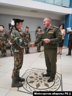 A student receives a certificate at the Valor Club's opening in Minsk.