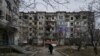 Цивил шета меѓу тешко оштетените станбени згради во Соледар, регионот Доњецк, 21 декември 2022 година