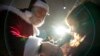 A man wearing a Santa Claus costume speaks to children at an aviation hangar during a Christmas event in Bucharest.