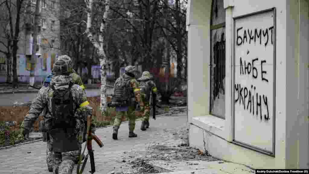 Ukrán katonák egy &bdquo;Bahmut szereti Ukrajnát&rdquo; feliratú graffiti mellett december 18-án