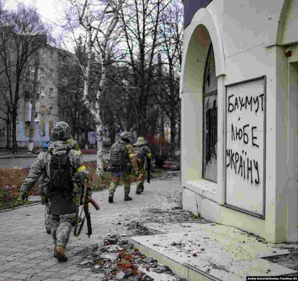 Украинские солдаты проходят мимо надписи &laquo;Бахмут любит Украину&raquo;, 18 декабря. И Россия, и Украина в настоящее время бросают людей и технику в бой за Бахмут, город в Донбассе, который имеет относительно небольшое военное значение, но стал местом ожесточенных сражений