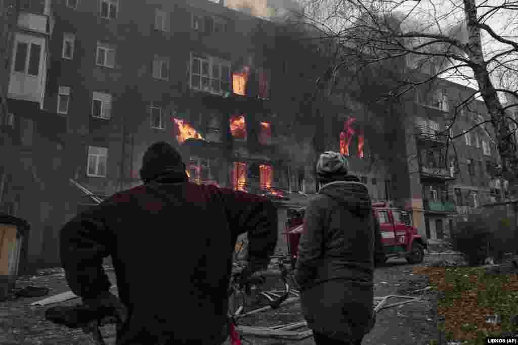 Locuitori ai Bahmutului privind cum le arde apartamentul, după bombardamentele din 7 decembrie.&nbsp; Înainte de invazia Rusiei, orașul avea o populație de 70.000 de locuitori și era cunoscut mai ales pentru mina de sare și pentru podgoriile sale.