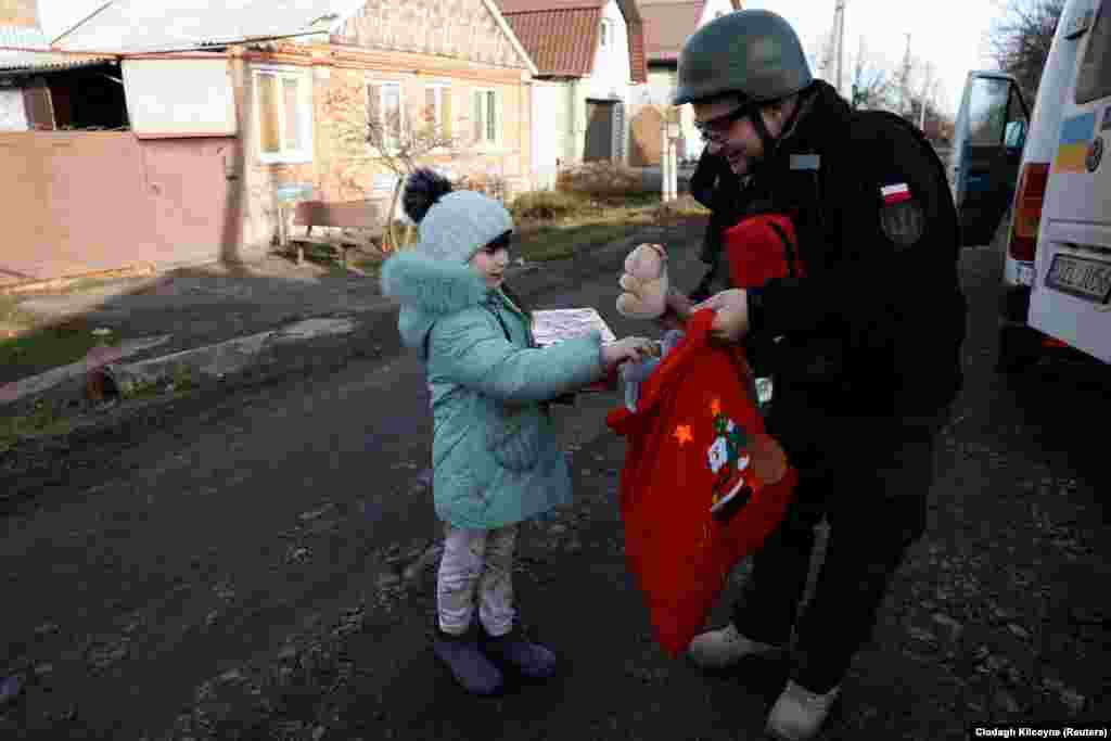 Kaszuwara, un polonez care s-a mutat la Kiev după începerea războiului, îi oferă Anhelinei, în vârstă de 6 ani, o pungă cu cadouri din care să aleagă.