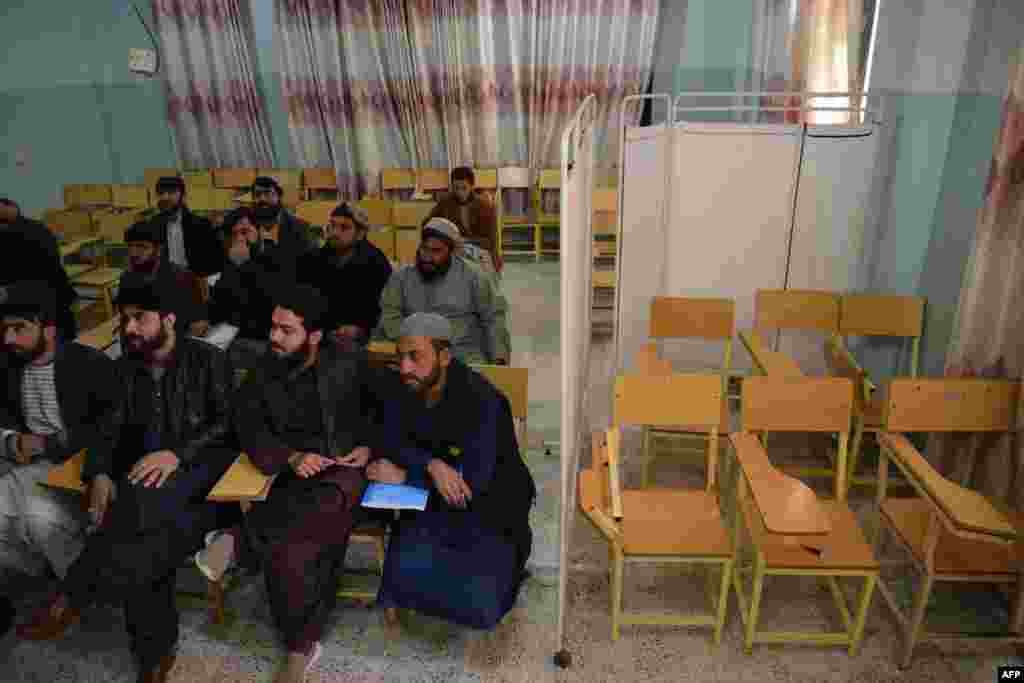 Male university students attend a class bifurcated by a curtain previously separating males and females at a university in Kandahar Province on December 21, the day the Taliban banned women from university education.