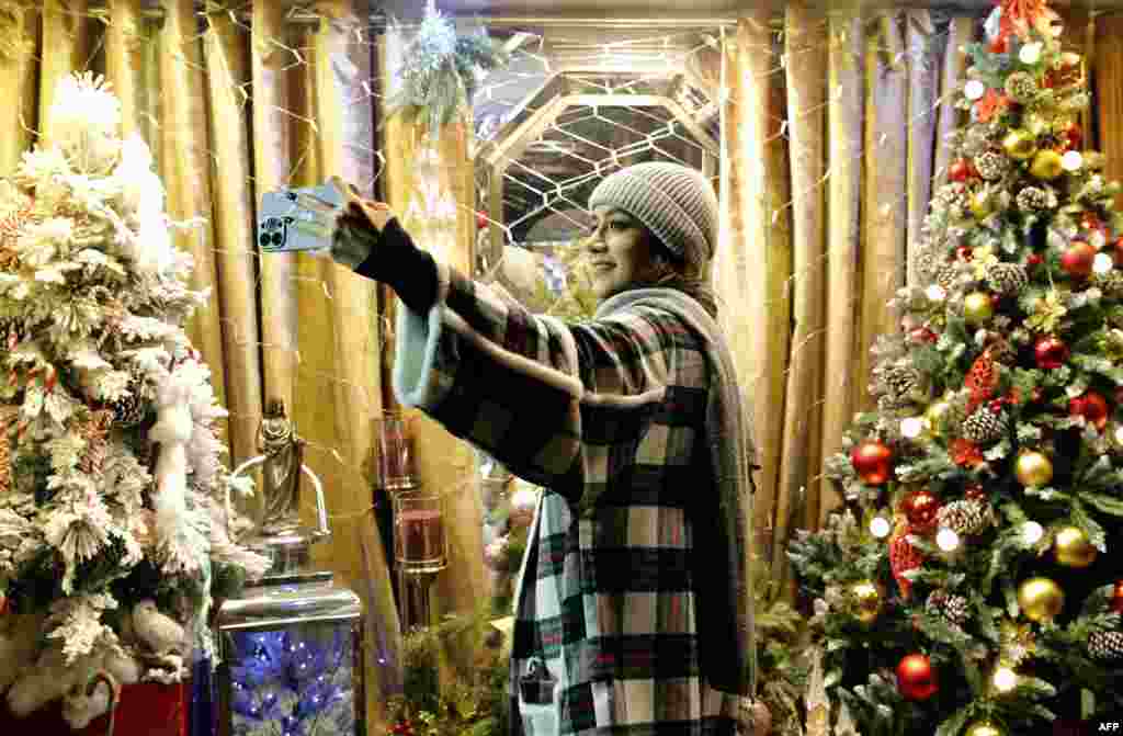 A young Iranian woman takes a selfie in front of Christmas trees in Tehran on December 25.&nbsp; In recent years, women deemed by the country&#39;s morality police to be flouting head-covering laws were made to attend a lecture on &quot;Islamic values.&quot; A family member was then permitted to collect them for release.