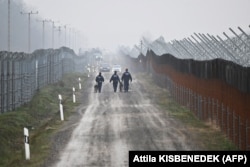 Policët kufitarë hungarezë me qen duke patrulluar përgjatë një gardhi me tela gjemborë të pajisur me kamera termike në kufirin me Serbinë, 15 dhjetor 2022.