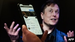 A 2022. április 14-én készült fotón Elon Musk Twitter-fiókja látható, a háttérben pedig ő maga Washingtonban. Több neves újságíró Twitter-fiókját felfüggesztették, miután Musk a családja veszélyeztetésével vádolta őket