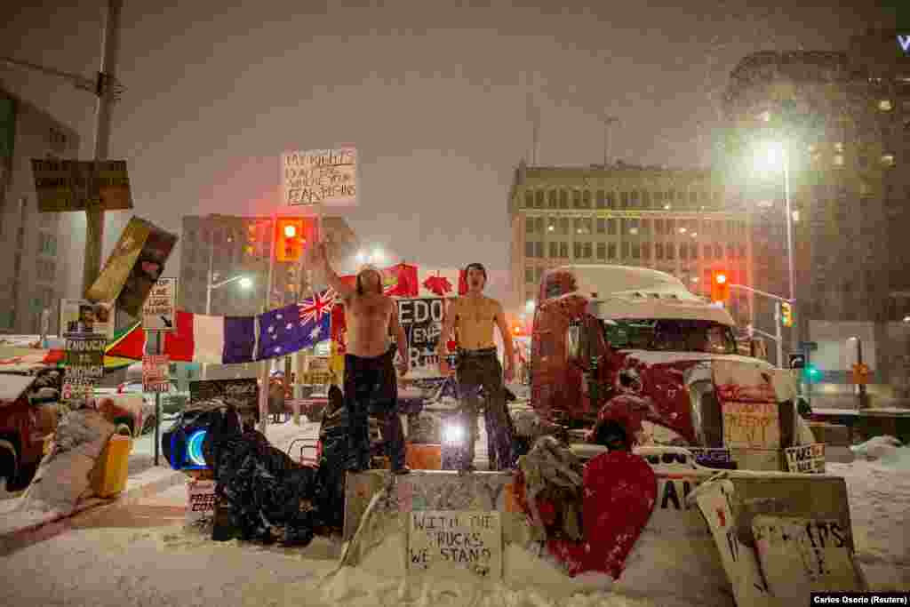 Two shirtless men scream while dancing during protests against the COVID-19 vaccine mandate along Wellington Street near the Parliament of Canada in Ottawa, Ontario, Canada, on February 17, 2022. (Reuters/Carlos Osorio)